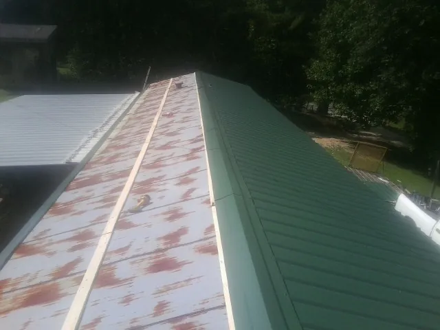 Old rusted panels beside newly installed green metal roofing — Wind Damage Roof Repair by Roofing Brothers in Sugarloaf