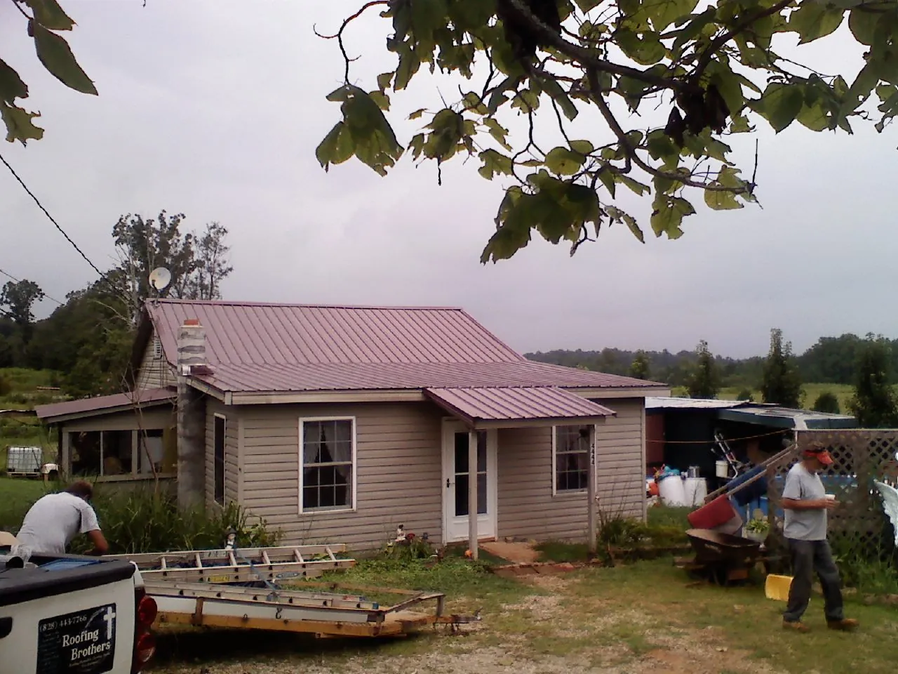 Crew finishing a mauve metal roof on a small farmhouse in Sugarloaf