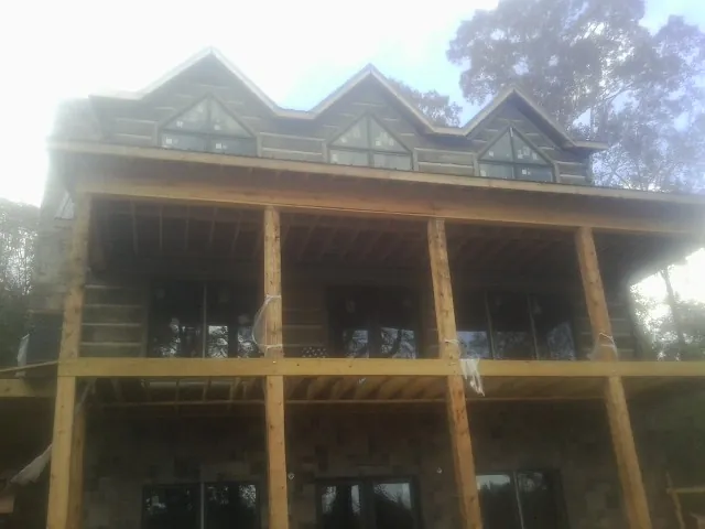 Dormers and porch framing on a large log home under construction — Roof Coating work by our crew in Sugarloaf