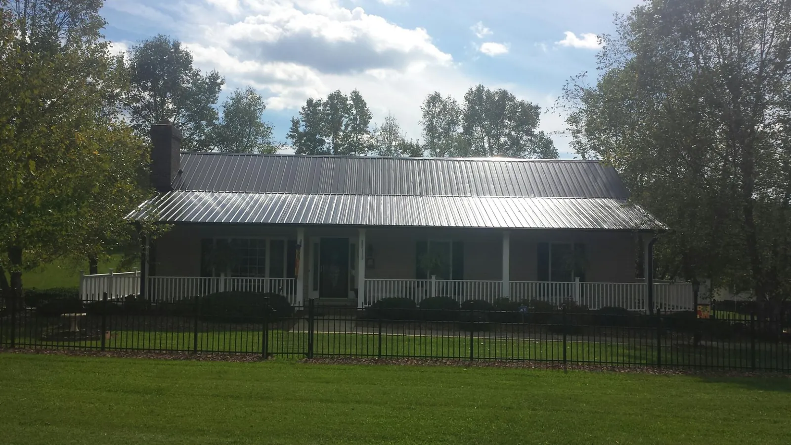 Gray metal roof on a brick ranch with a full width front porch — Gutter Guard Installation work by our crew in Sugarloaf