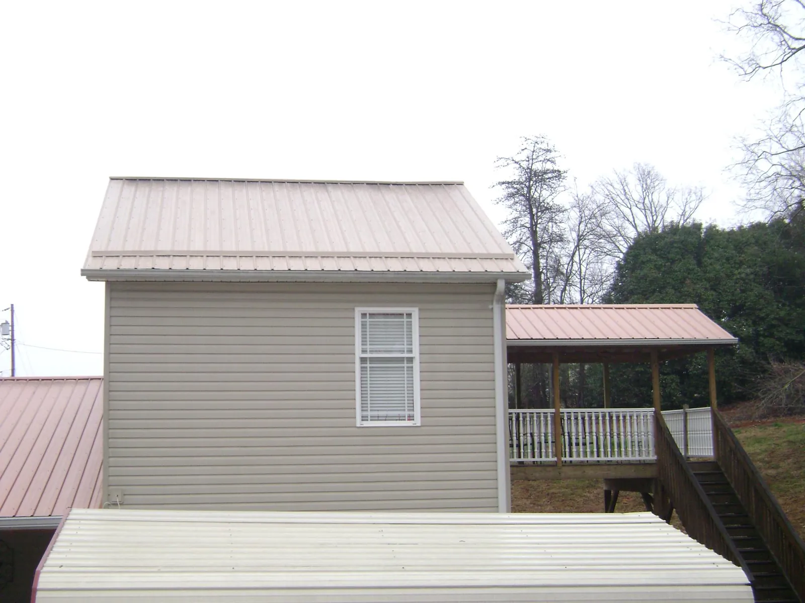 Tan metal roofs on a two story addition and attached porch, from a Roof Replacement job in Sugarloaf