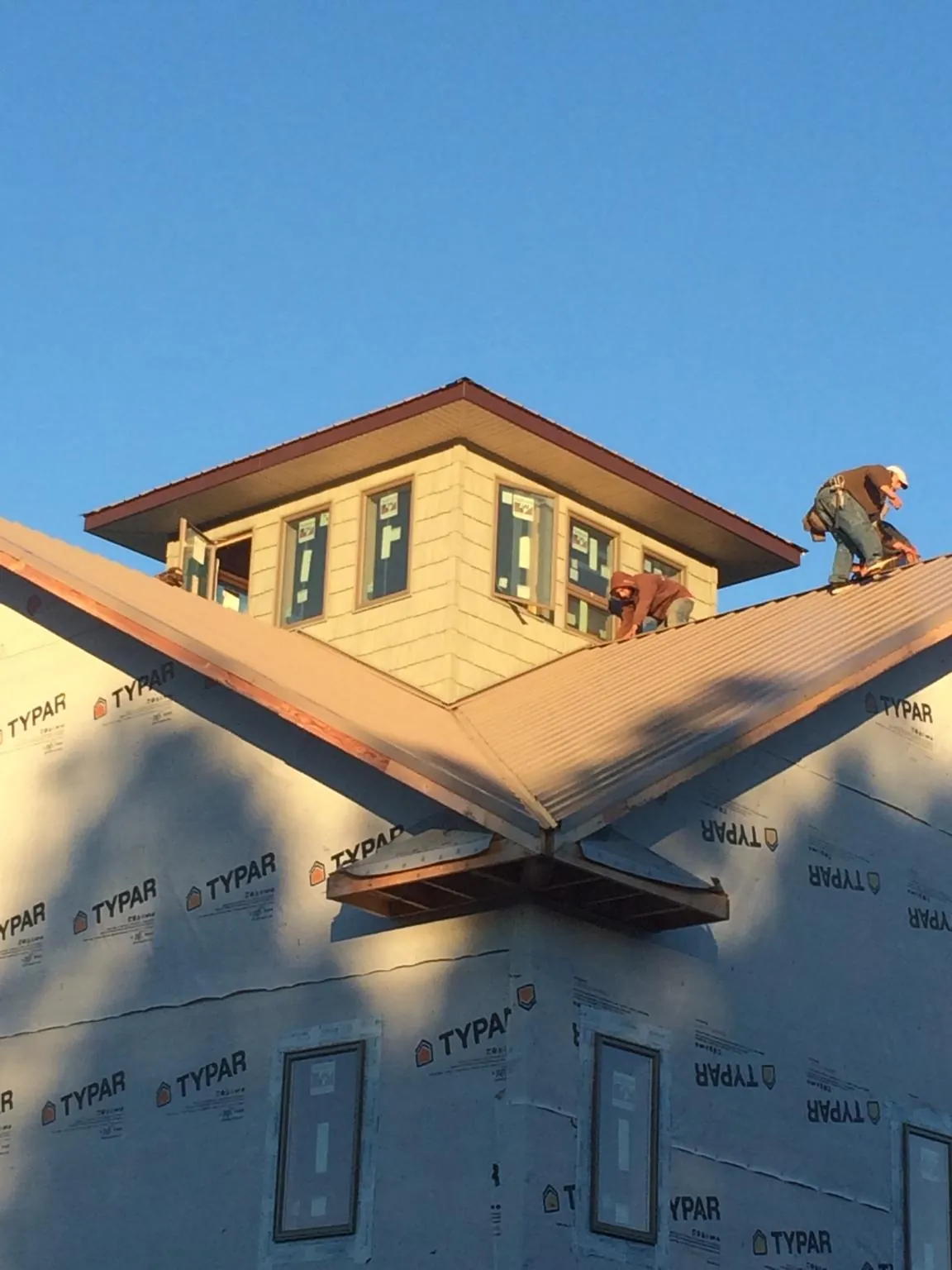 Roofers working around a rooftop cupola on a new metal roof at sunset — Roof Waterproofing in Sugarloaf by Roofing Brothers